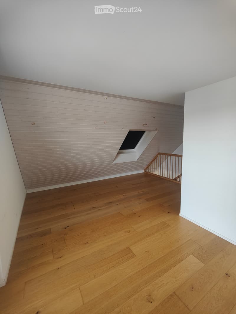 Empty room with wooden flooring, white walls, and a small window opening to the side.