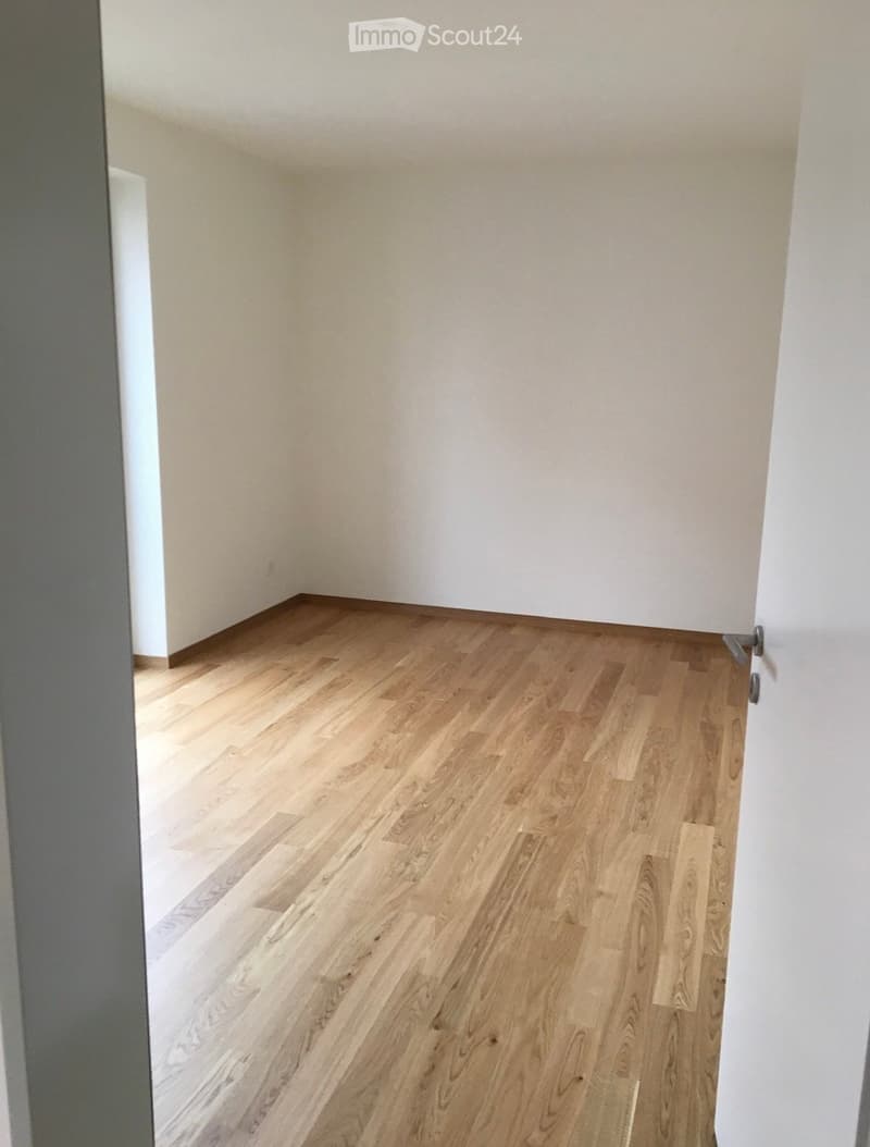 Empty room with light wooden flooring and white walls, no furniture or equipment visible.