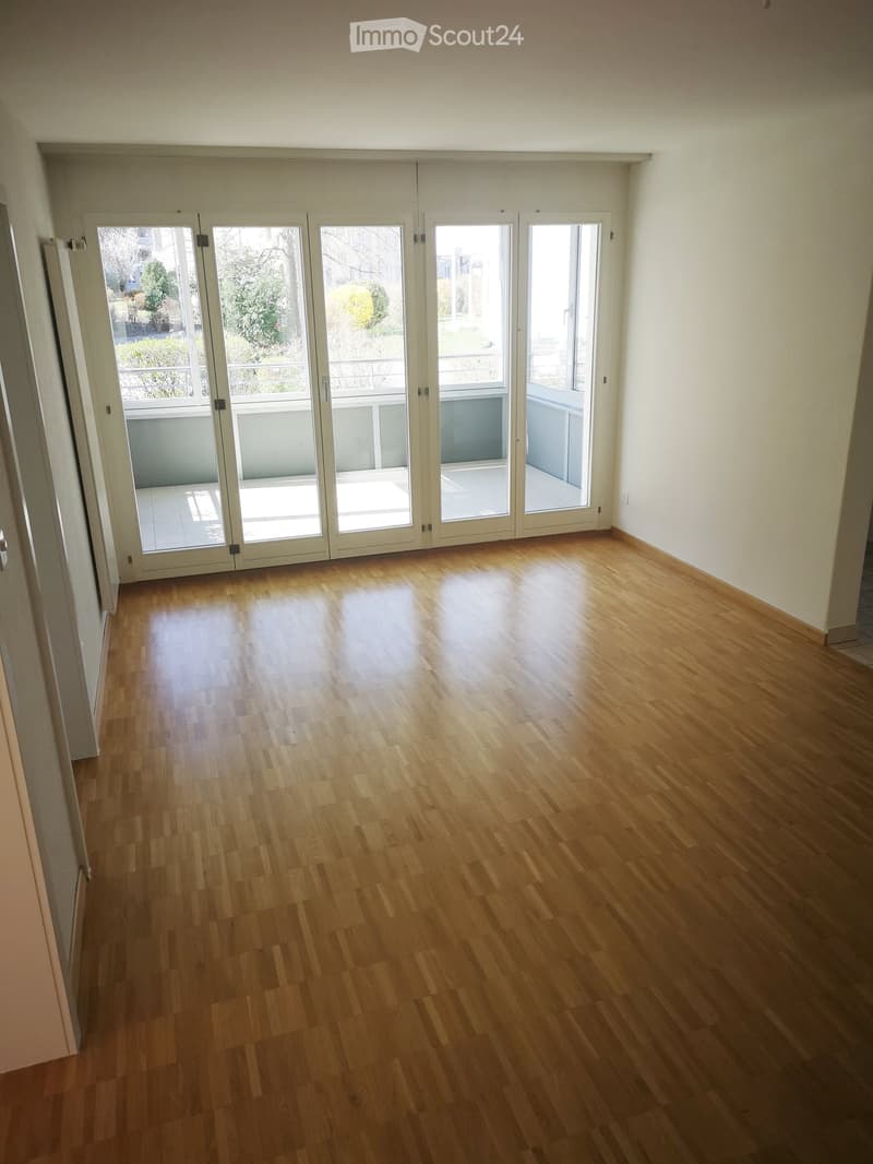 Empty room with wooden flooring and large sliding glass doors leading to a balcony area.
