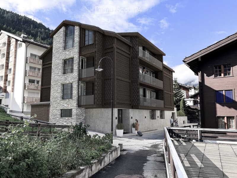 Modern multi-story building with stone and wood facade, large windows, balconies, and surrounding greenery.