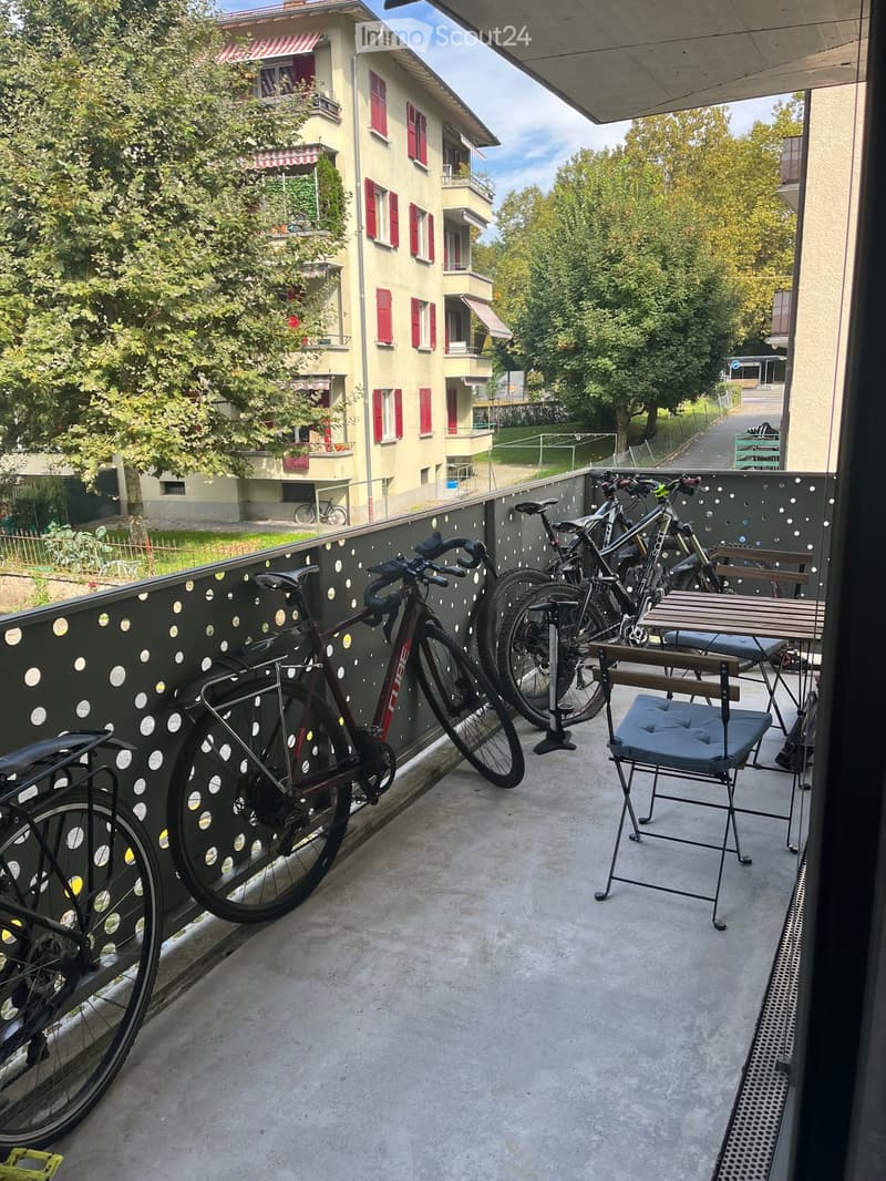 Balcony with a table, chair, and several bicycles parked against a decorative fence.