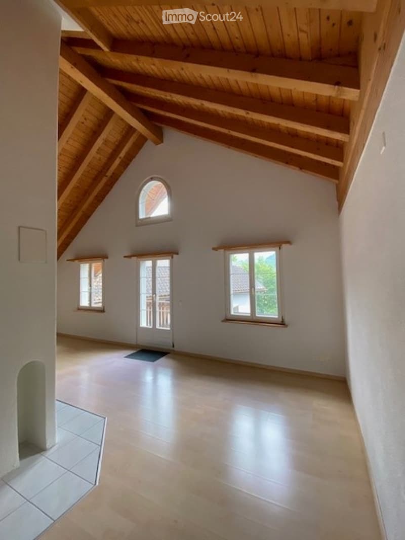 Bright, empty room with wooden beams on the ceiling, large windows, and a tiled floor. No furniture or equipment present.