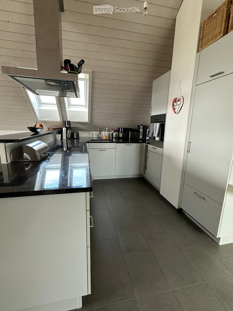 Modern kitchen with white cabinets, black countertops, and stainless steel appliances. Features include an oven, fridge, sink, and various small appliances on the counter.