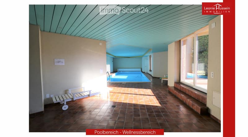 Wellness area with indoor swimming pool, tiled floor, lounge chairs, and large windows offering natural light.