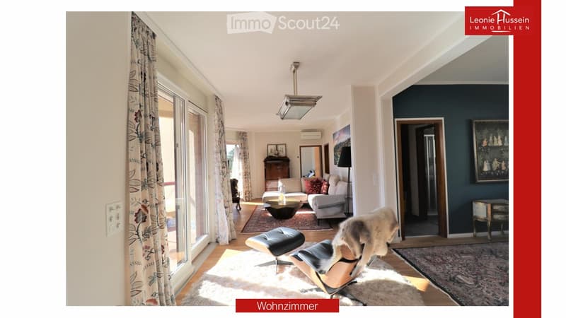 Bright living room with large windows, a sofa, coffee table, ottoman, chair, mirror, and picture frame.