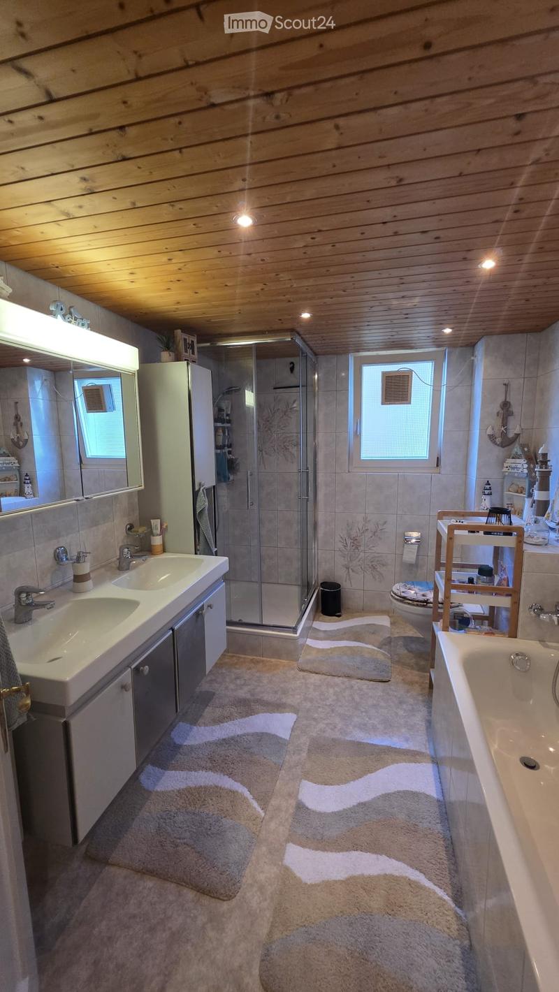 Bathroom with double sink, bathtub, shower, and wooden ceiling. Includes mirrors, cabinets, and decorative bathmats.
