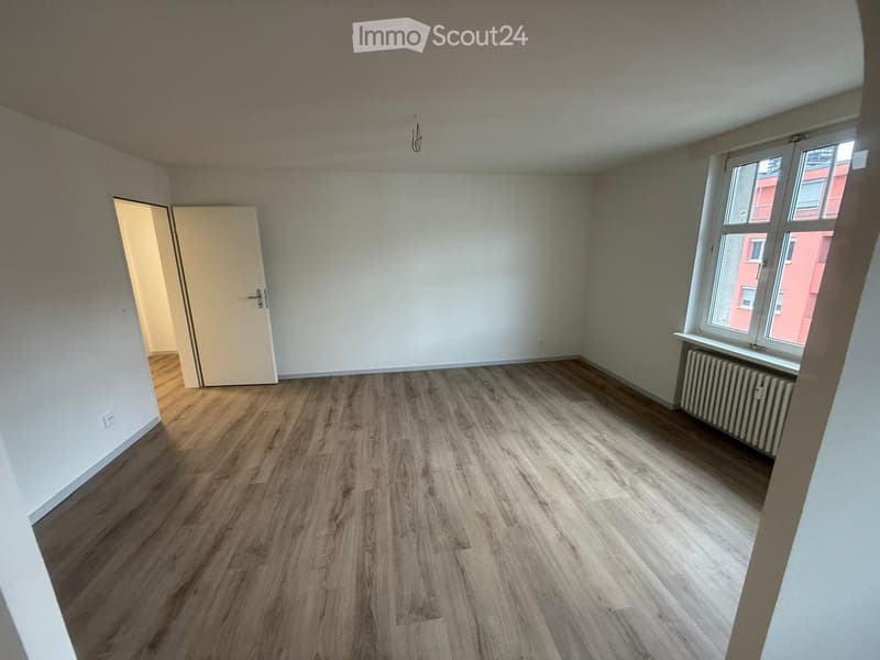Empty room with wooden floors, white walls, glass windows, door, radiator