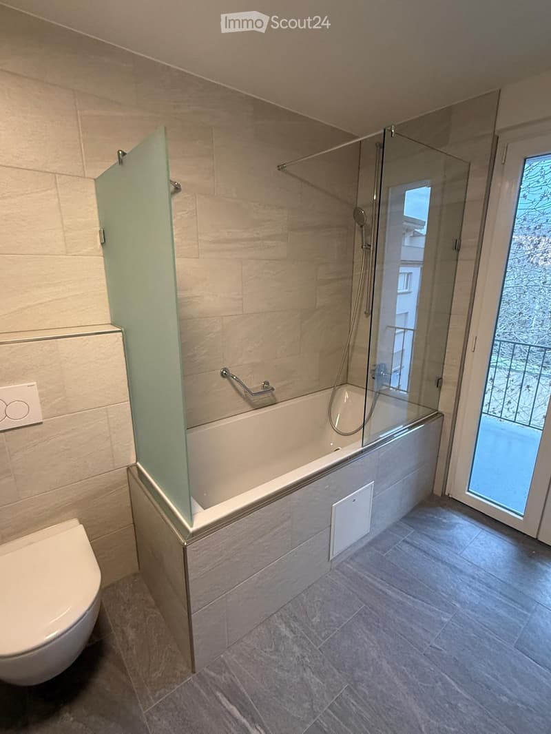modern bathroom with bathtub, glass door, and balcony access