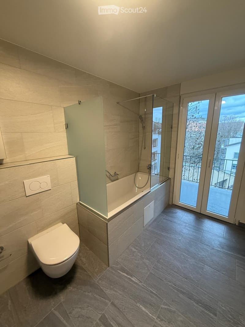 Bathroom with bathtub, separate shower, toilet, and glass door leading to a balcony with view