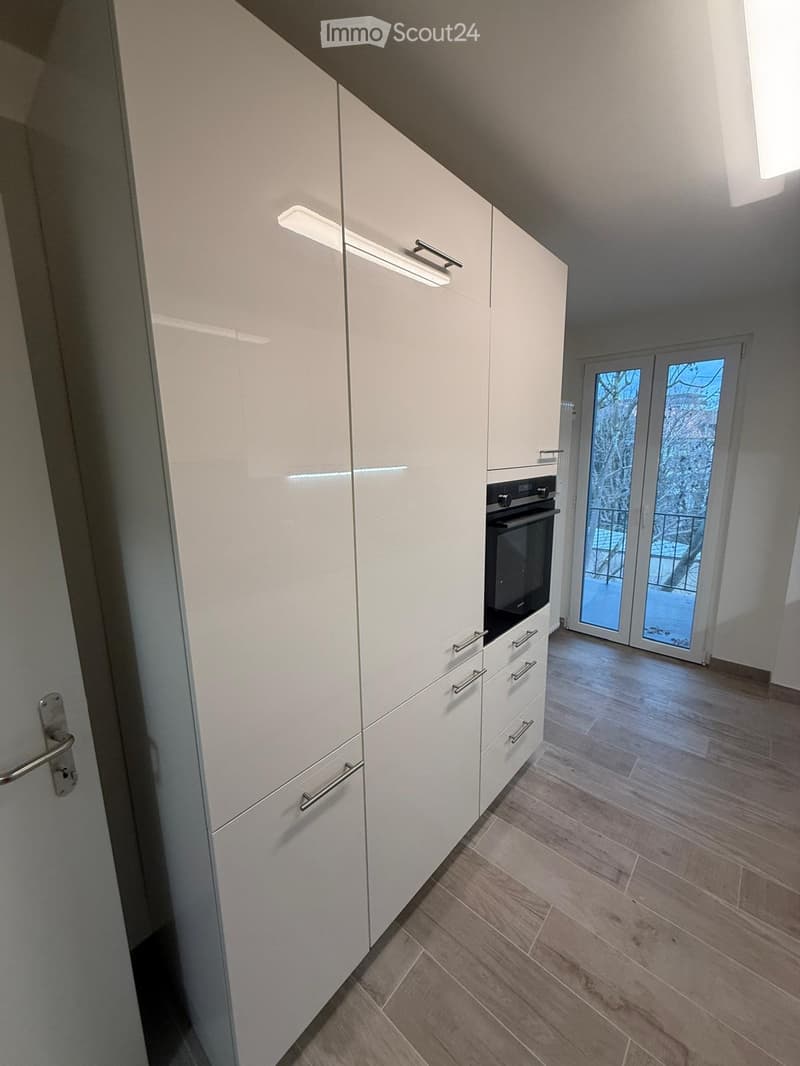white cabinetry, built-in oven, glass double doors to balcony