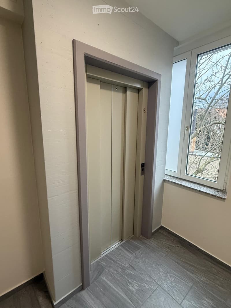 elevator shaft, light gray tile flooring, white walls, window