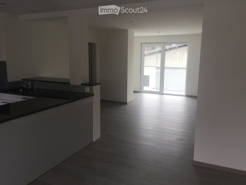 Empty room with wooden flooring, white walls, and a sliding glass door leading to a balcony.
