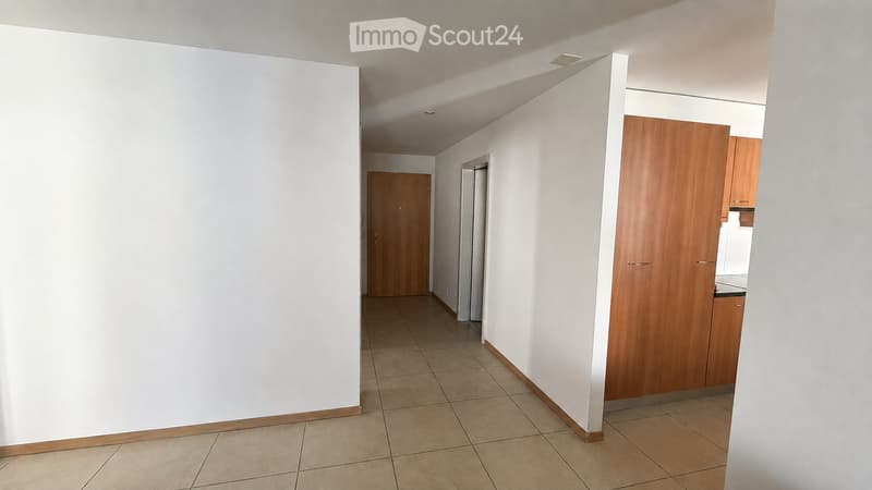 Empty hallway with tiled floor, white walls, and wooden doors leading to other rooms.
