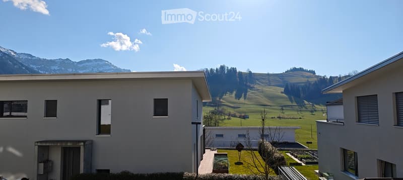 White modern house, flat roof, 3 floors, large window, grassy hill
