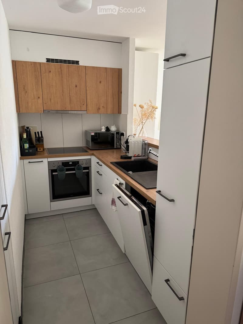 Modern kitchen with white and wooden cabinets, stainless steel appliances, and a wooden countertop.