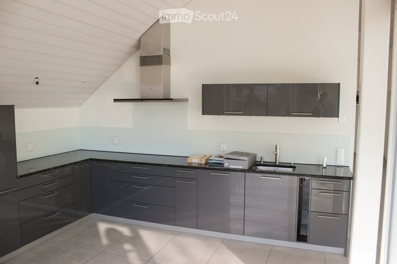 Modern kitchen with grey cabinets, black countertops, stainless steel appliances, and a sleek design.