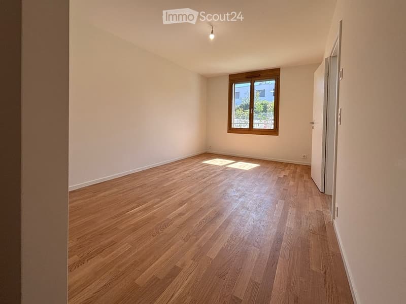 Empty room with wooden flooring, white walls, and a single window with wooden frame. No furniture or equipment present.