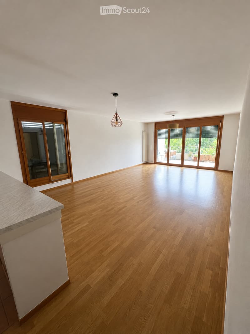 Empty room with wooden flooring, white walls, and large sliding glass doors leading to an outdoor area.