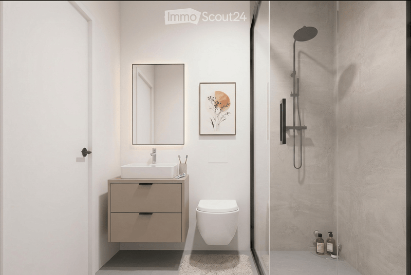 Modern bathroom with a sink, mirror, toilet, and a glass-enclosed shower with a handheld showerhead. The sink has a sleek wooden vanity with two drawers, and a picture frame hangs on the wall above the sink.