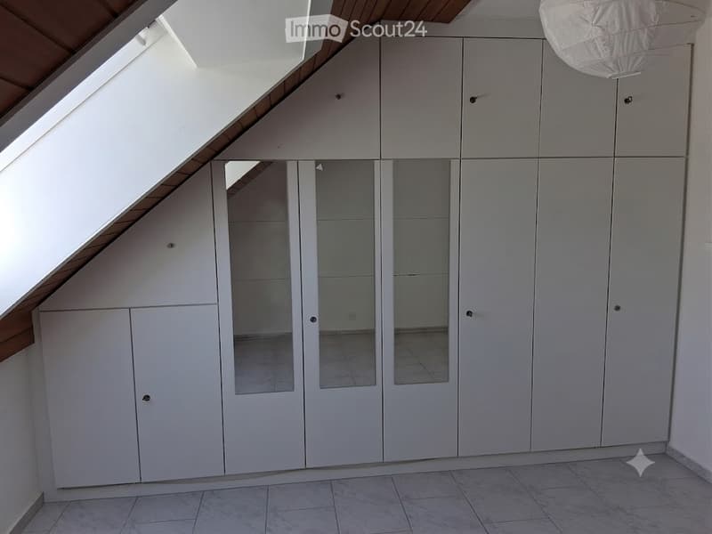 Empty room with white built-in wardrobes, tiled floor, and skylight window.