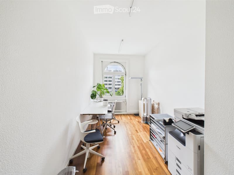 empty office with light wooden floor, white walls, white office furniture, and one desk by the window