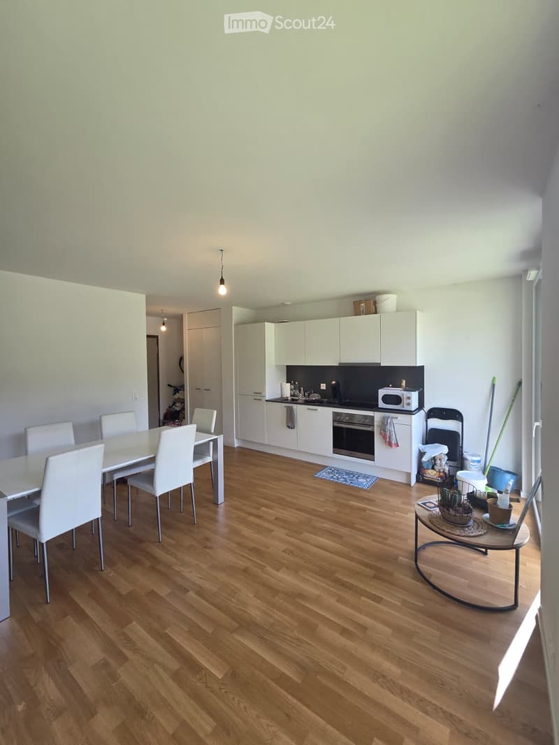 Open-plan kitchen and dining area with white cabinets, a dining table with chairs, and a small round table with a chair.