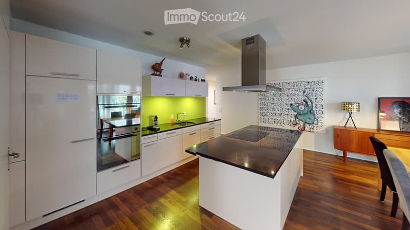 Modern kitchen with white cabinets, stainless steel appliances, a central island with black countertop, and a dining area with a wooden table and chairs.