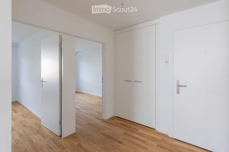 Empty room with light wooden flooring, white walls, and white cabinetry. No furniture or personal items are present.