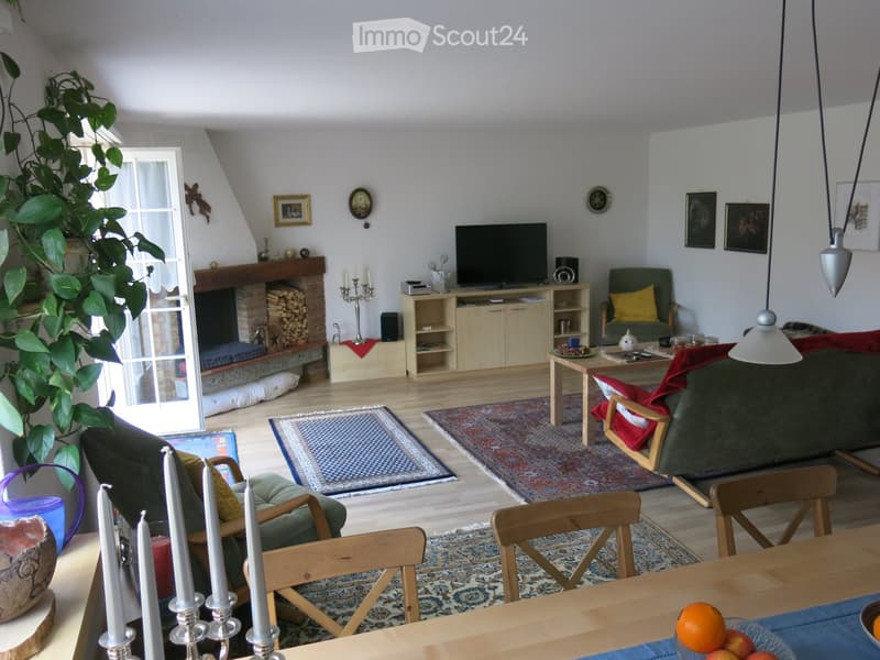 Living room with fireplace, sofa, coffee table, armchair, dining table, chairs, television, candle holders, and decorative items.
