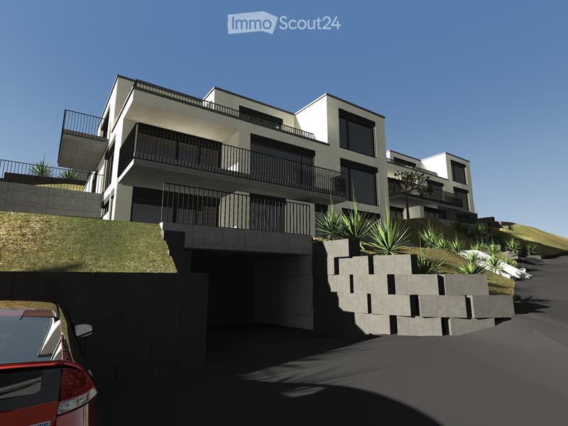Modern multi-story residential building with balconies, surrounded by landscaped greenery and a raised ground floor entrance.