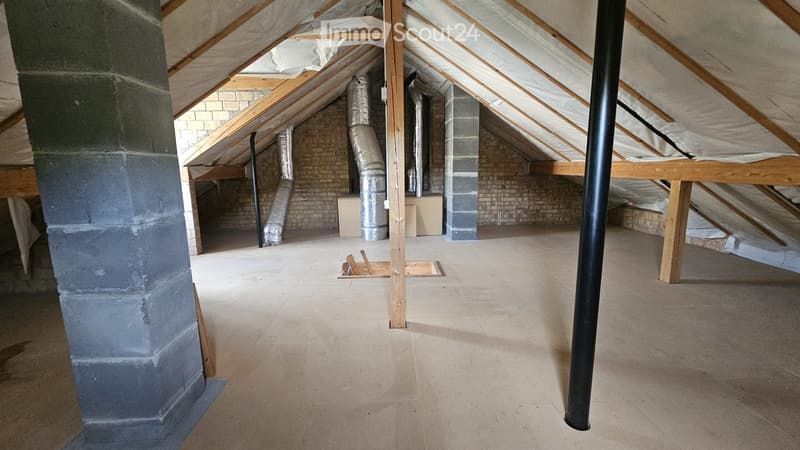 Empty attic space with exposed wooden beams, brick walls, and insulation. No furniture or equipment present.