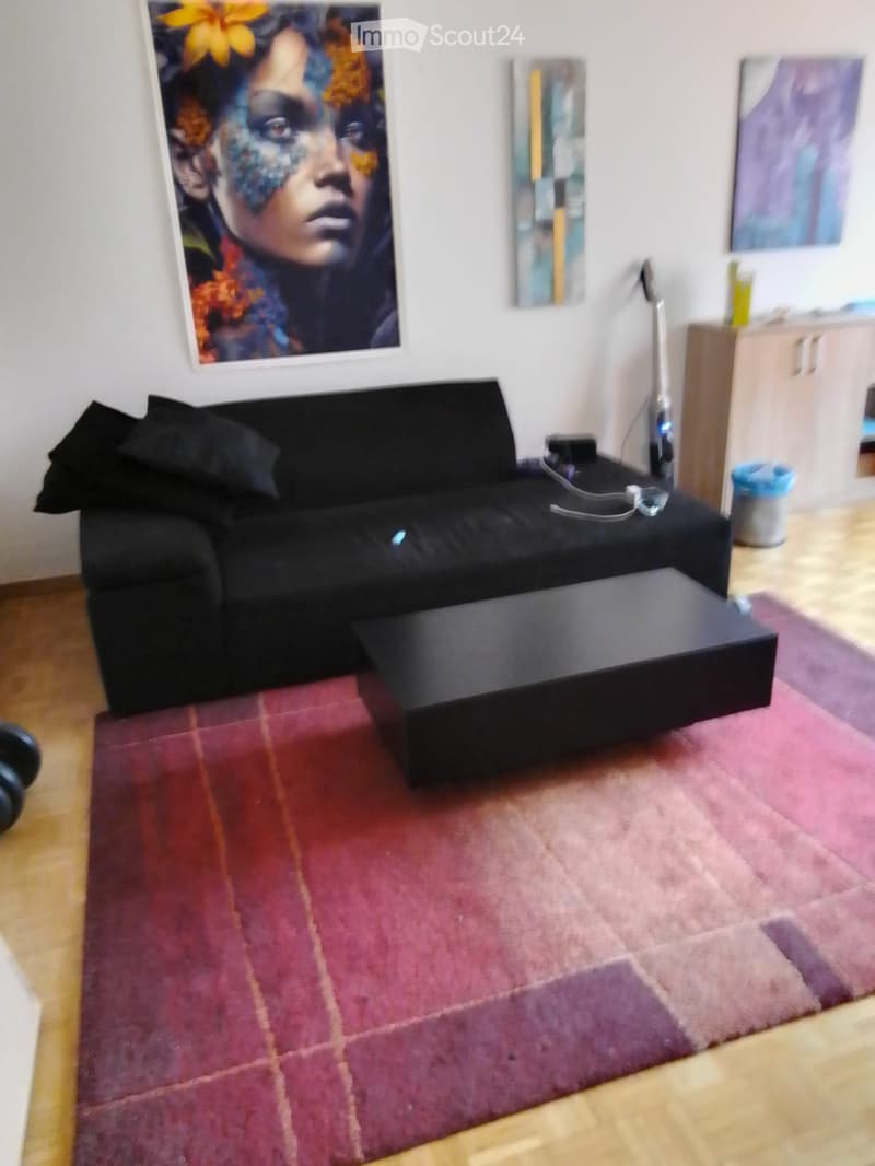 Modern living room with a black sofa, coffee table, floor lamp, and a colorful abstract painting on the wall.
