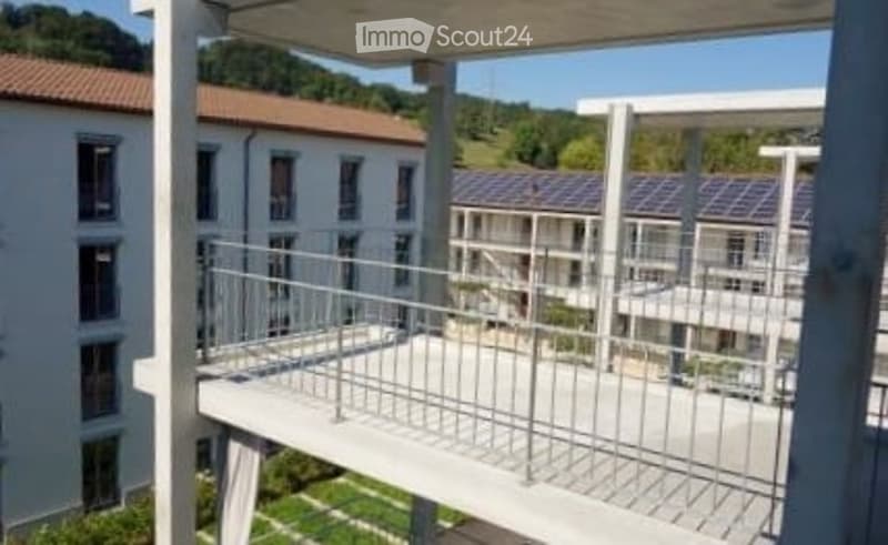 Balcony overlooking a modern residential complex with multiple buildings and a landscaped garden area below.