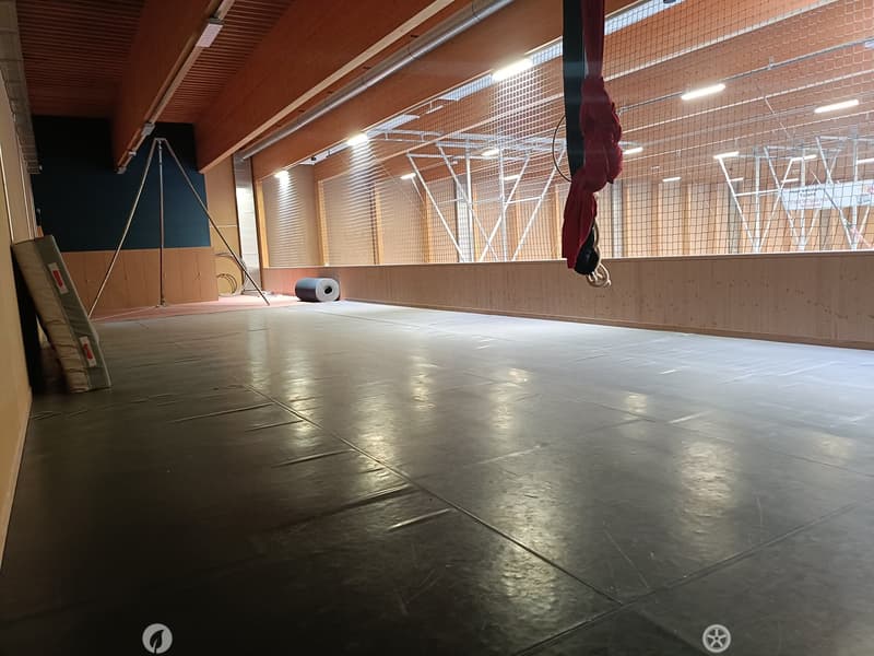 Empty room with polished concrete floor, wooden ceiling, large windows with blinds, and minimal equipment.