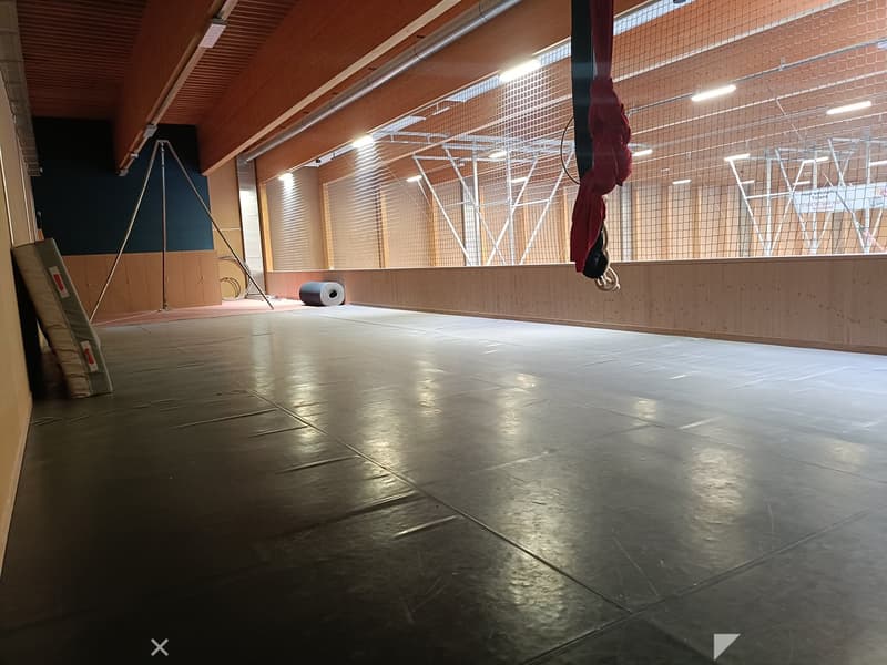 Empty room with polished concrete floor, wooden ceiling, large windows with blinds, and minimal equipment.
