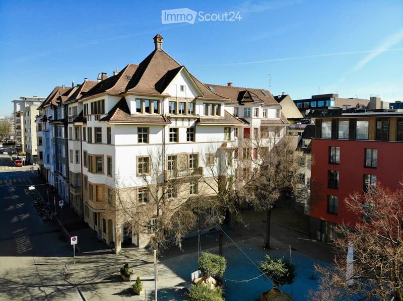 A multi-story residential building with a classic architectural style, featuring a tiled roof, multiple windows, and a well-maintained facade.