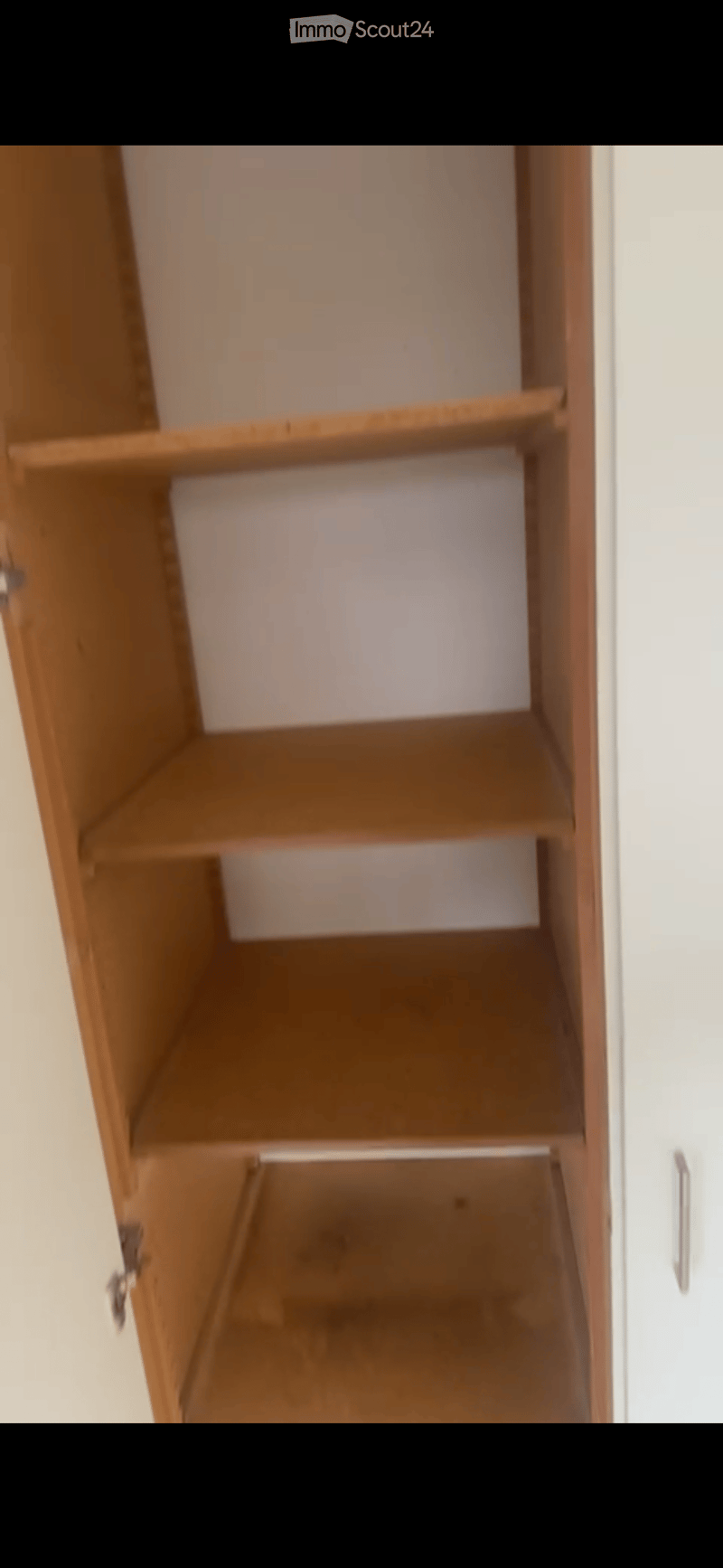 Empty wooden closet with multiple shelves and a bottom drawer, no items inside.