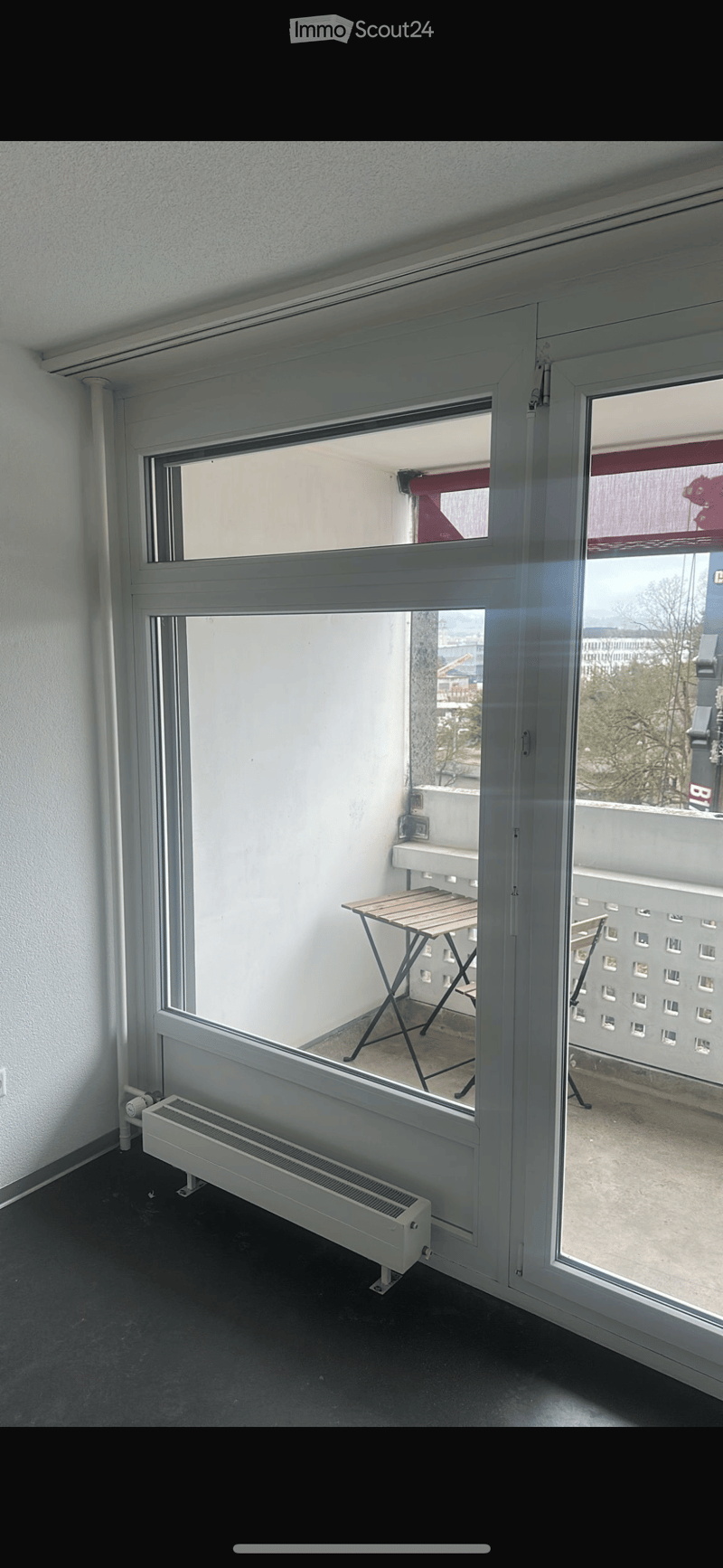 Balcony with a small wooden table and a radiator visible in the adjacent room.