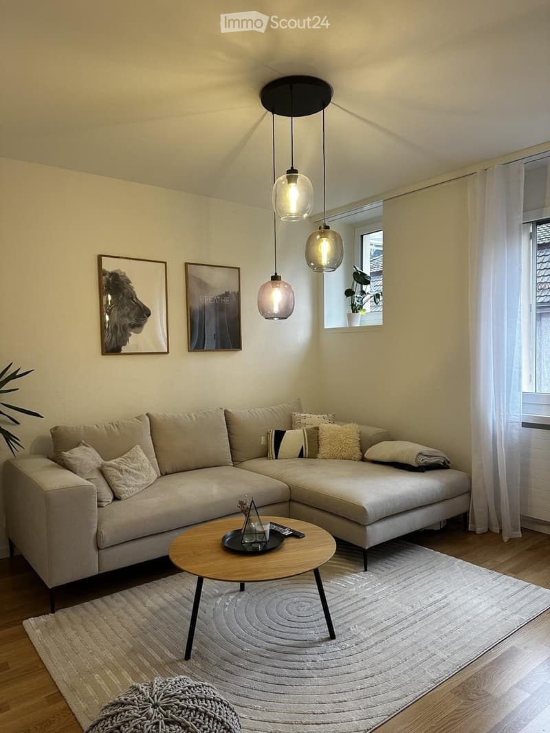 Modern living room with a beige sectional sofa, wooden coffee table, floor lamp, and decorative pillows.