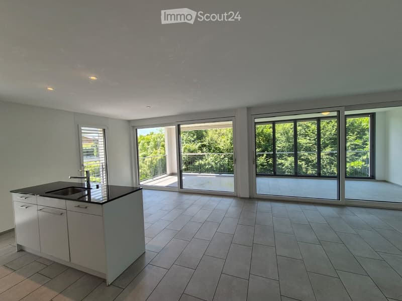 Empty kitchen with white cabinets, a sink, and large sliding glass doors leading to a balcony.
