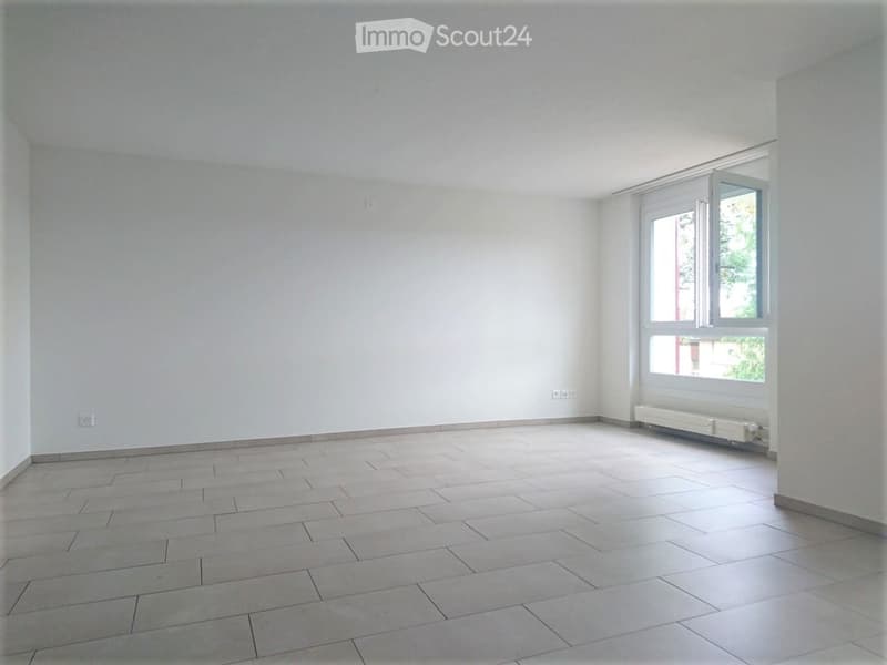 Empty room with tiled floor, white walls, and a large window with white frame. No furniture or equipment present.