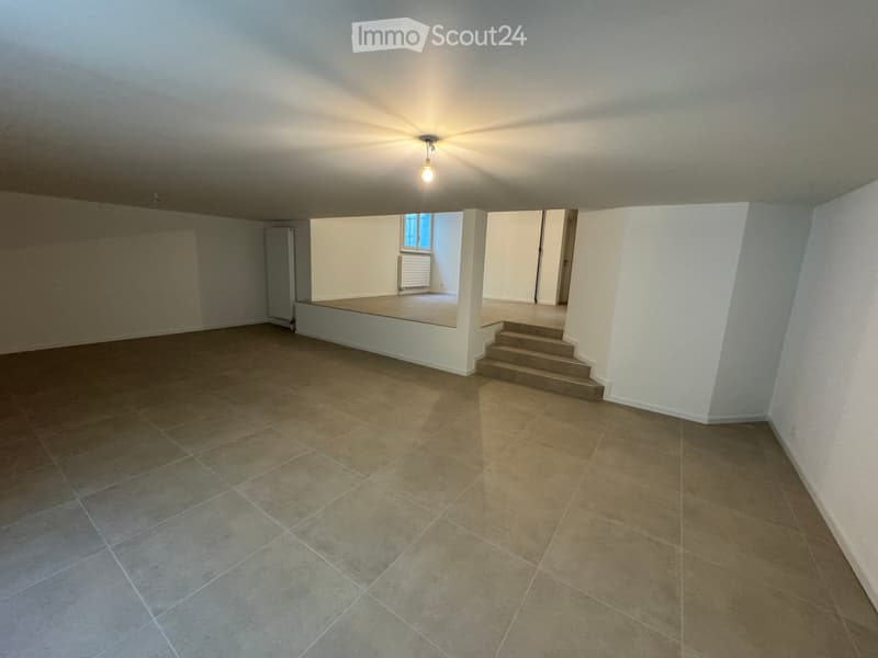Empty room with tiled floor, white walls, and a small window. Stairs lead to another area.