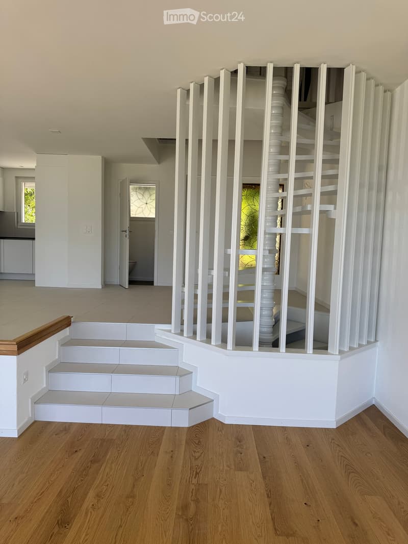Modern hallway with wooden flooring, white staircase with white balustrade, and open doorway leading to another room.