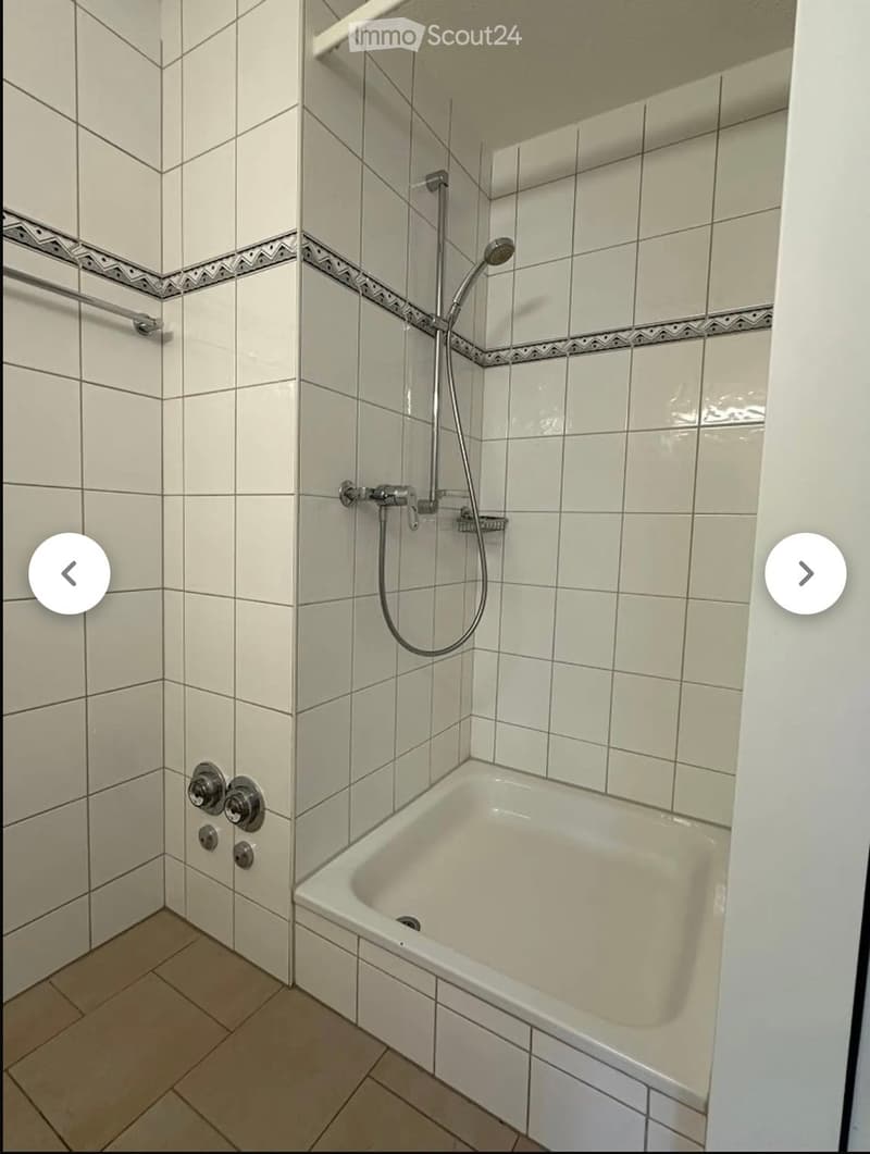 Bathroom with a bathtub, tiled walls, and a showerhead attached to the wall.