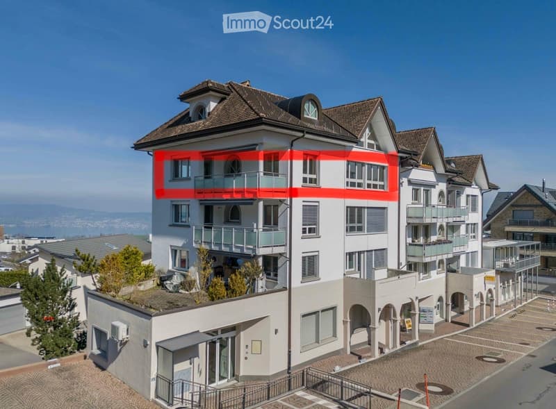 Multi-story residential building with balconies, large windows, and a scenic view of the surrounding area.