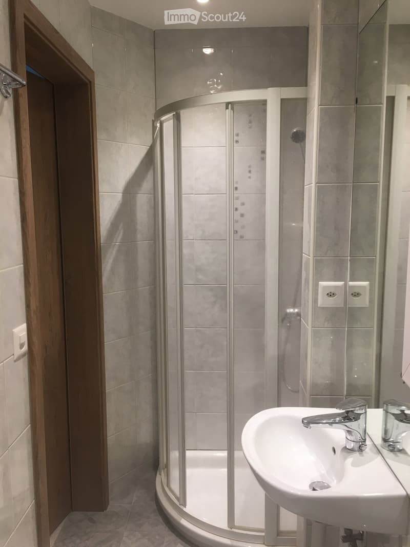 Modern bathroom with a white sink, chrome faucet, and a glass-enclosed shower stall.