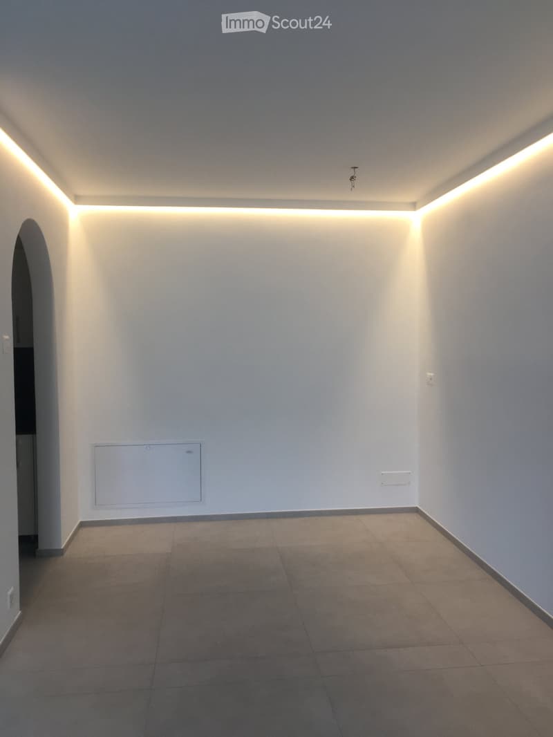Empty room with white walls, tiled floor, and built-in lighting along the ceiling edges.