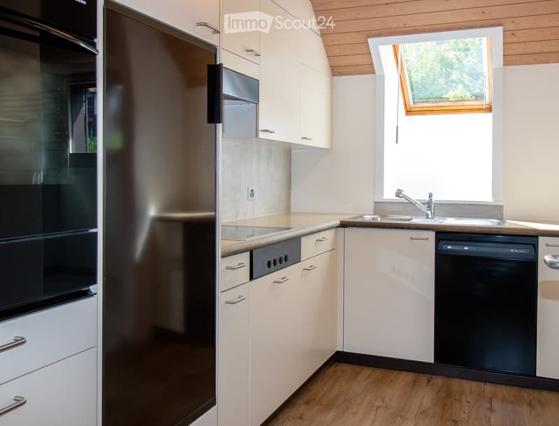 Modern kitchen with light-colored cabinets, stainless steel appliances, and wooden flooring.