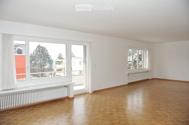 open room with balcony, large windows, wooden parquet flooring, white radiators