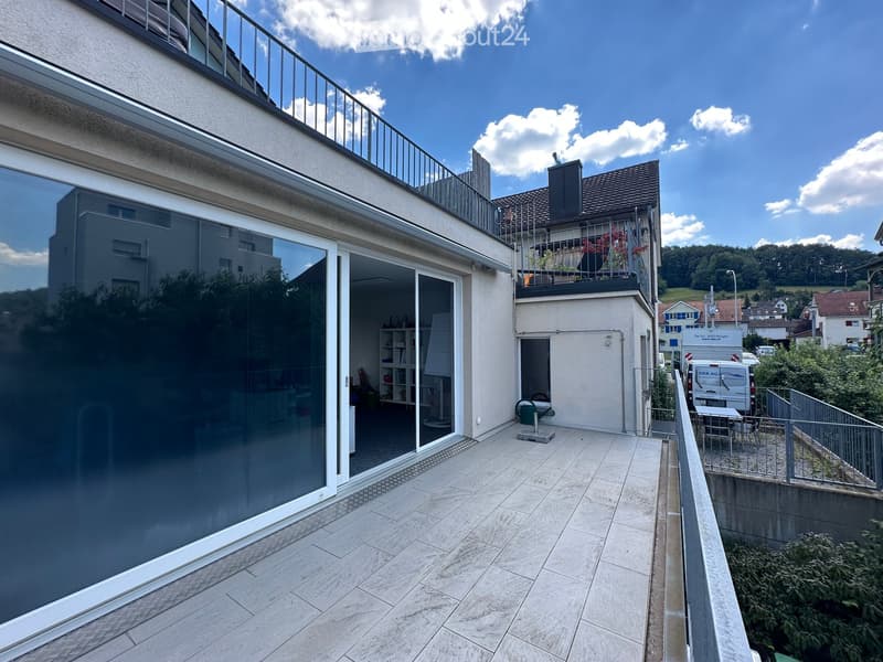 Balcony with tiled floor, glass sliding door leading to interior, metal railing, and small table and chairs.